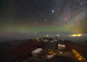 In this new ESO image, nightfall raises the curtain on a theatrical display taking place in the cloudless skies over La Silla. In a scene humming with activity, the major players captured here are Comet Lovejoy, glowing green in the centre of the image; the Pleiades above and to the right; and the California Nebula, providing some contrast in the form of a red arc of gas directly to the right of Lovejoy. A meteor adds its own streak of light to the scene, seeming to plunge into the hazy pool of green light collecting along the horizon. The telescopes of La Silla provide an audience for this celestial performance, and a thin shroud of low altitude cloud clings to the plain below the observatory streaked by the Panamericana Highway. Comet Lovejoy’s long tail is being pushed away from the comet by the solar wind. Carbon compounds that have been excited by ultraviolet radiation from the Sun give it its striking green hue. This is the first time the comet has passed through the inner Solar System and ignited so spectacularly in over 11 000 years. Its highly elliptical orbit about the Sun — adjusted slightly due to meddling planets — means that it will not grace our skies for another 8000 years once it has rounded the Sun and begun its lonely voyage back into the cold outer regions of the Solar System. This image was taken by ESO Photo Ambassador Petr Horálek during a visit to La Silla in January 2015. The sky in this image was captured with a series of long exposures, resulting in the wonderful vista of the comet in the sky. However, the bottom half uses only one of these exposures in order to retain the sharpness of the La Silla landscape.
